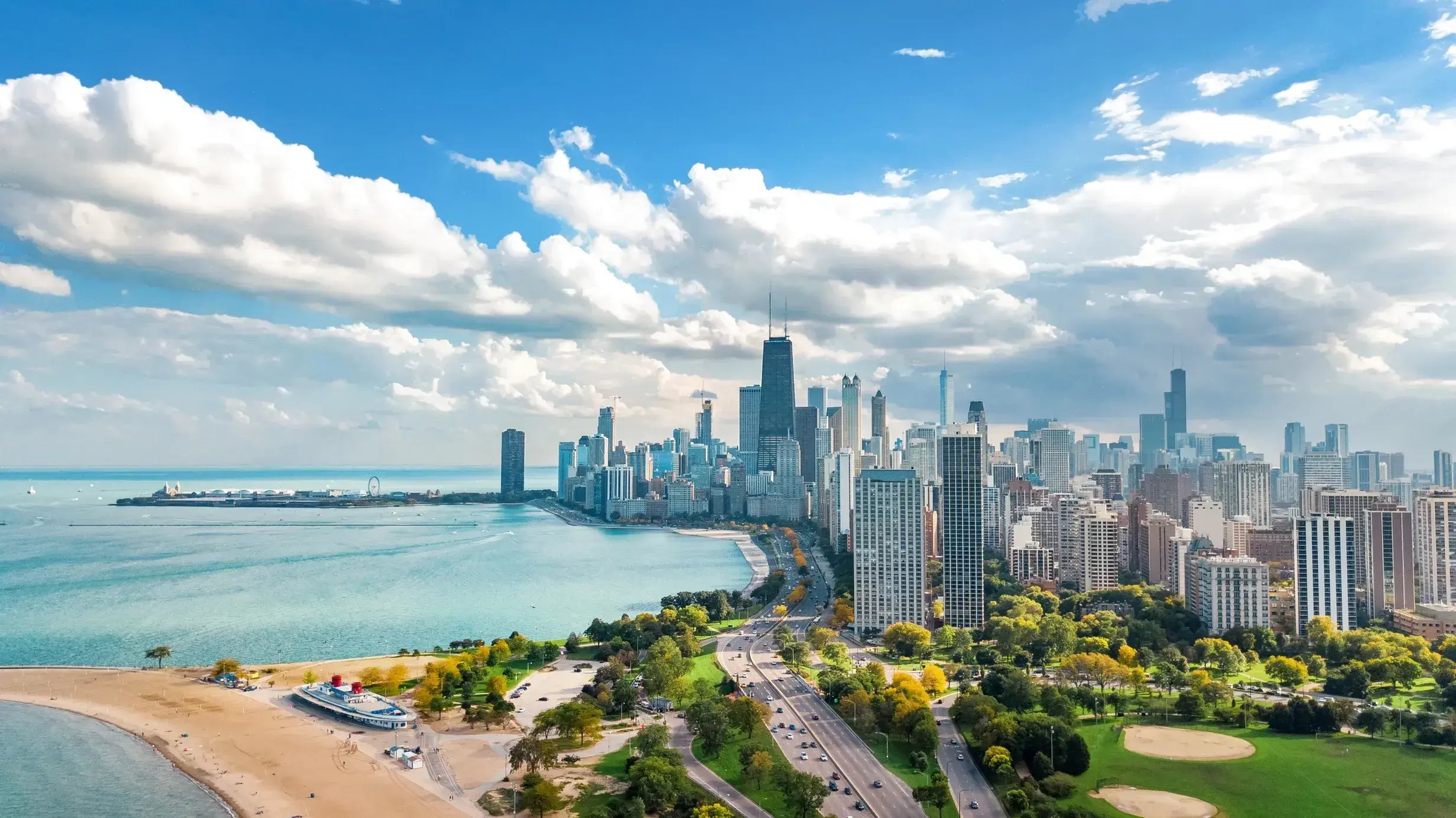 Aerial view of the Chicago skyline and Lake Michigan, with Lake Shore Drive running along the waterfront.
