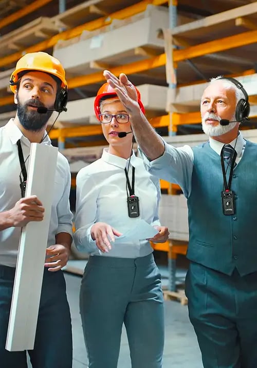 People in hardhats and headsets on a tour through a ware house.