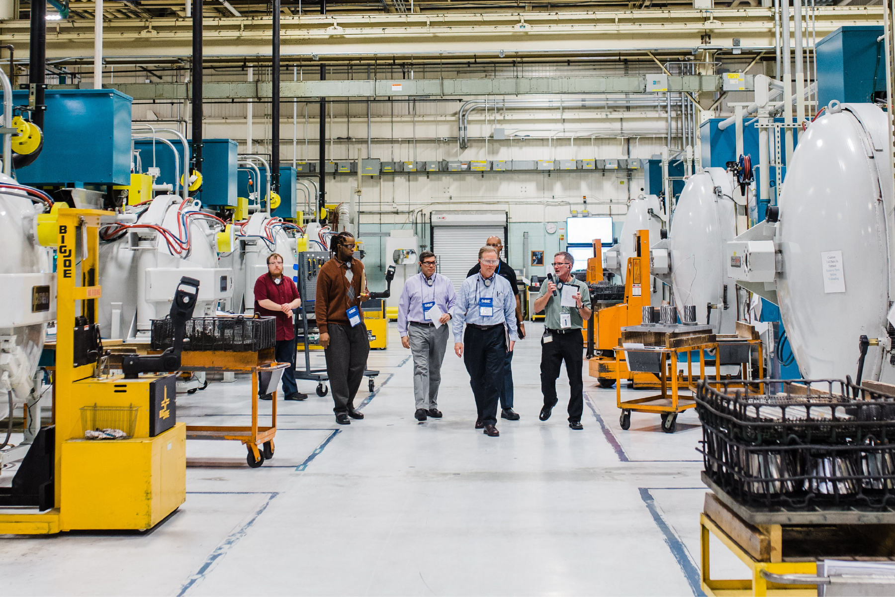 Two people walking and talking through an active manufacturing production floor