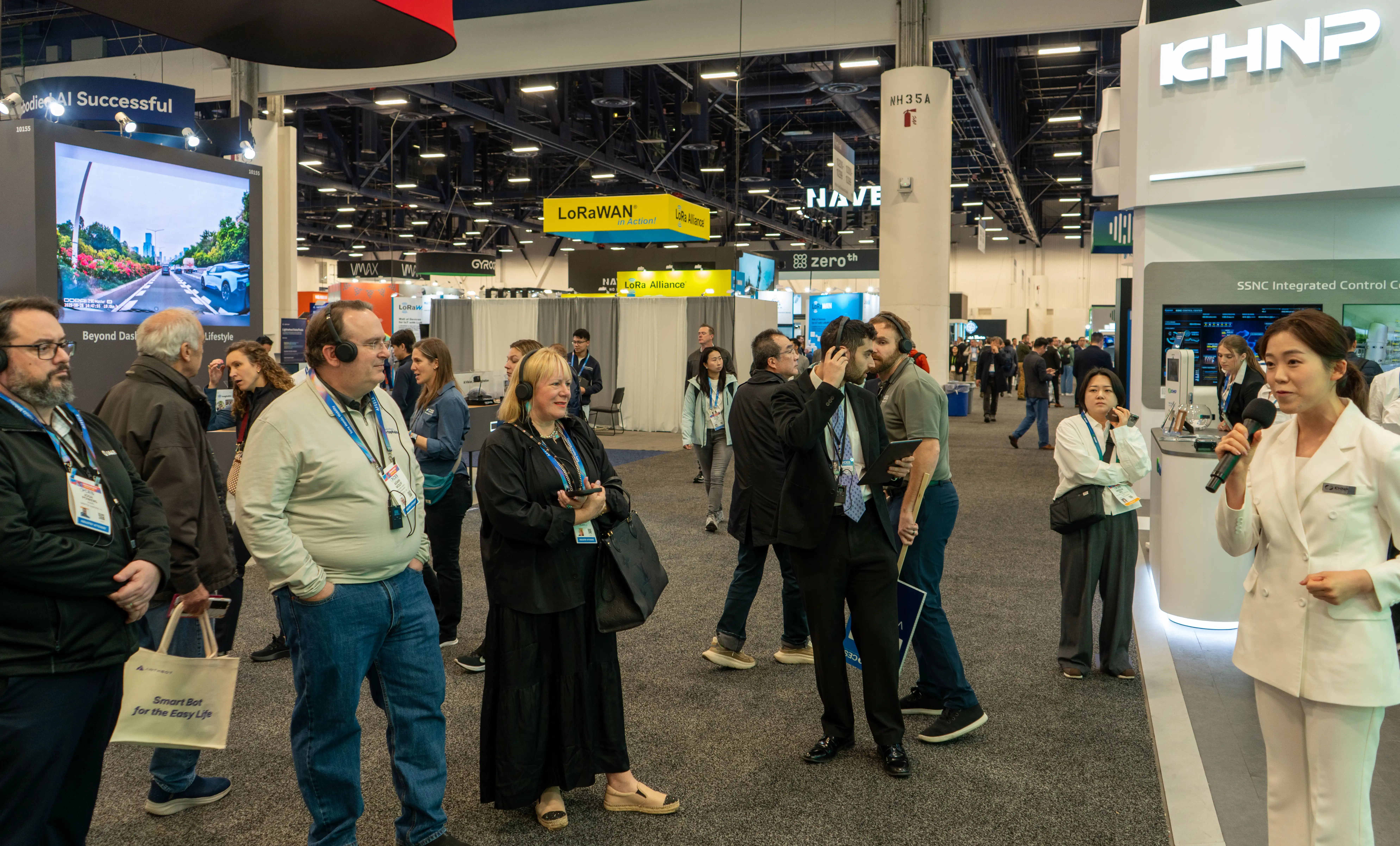 Live presentation on a busy trade show floor with attendees using wireless headsets for clear communication.